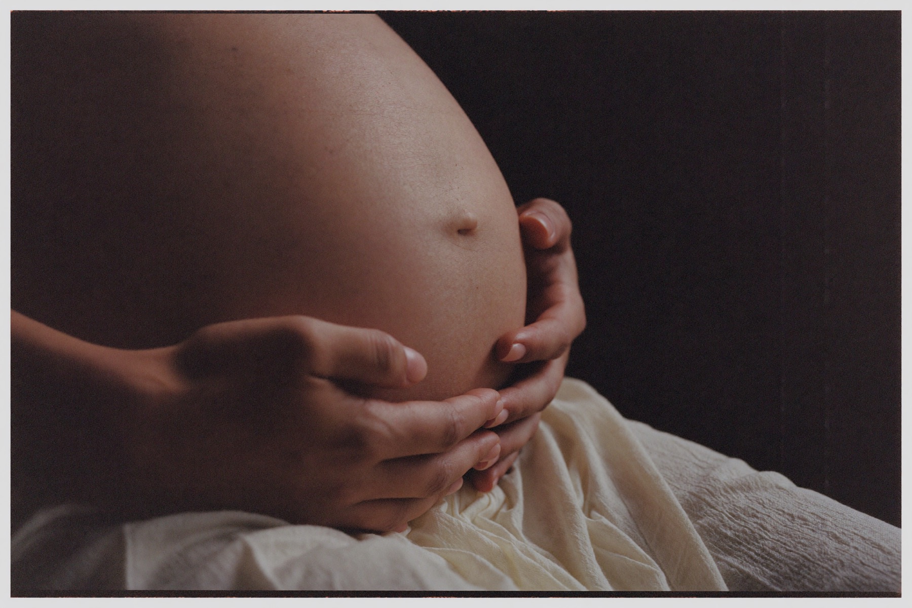 A practitioner assessing tissue tension across a pregnant abdomen